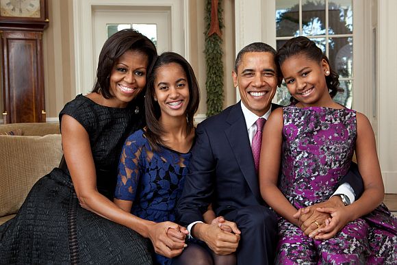 President Barack Obama, First Lady Michelle Obama, and their daughters, Malia, left, and Sasha, right, sit for a family portrait in the Oval Office