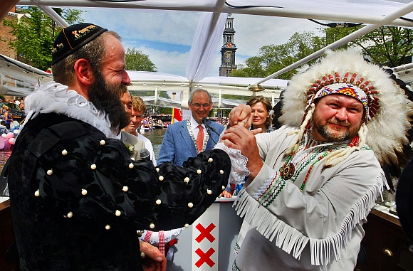Scott Brown, dressed as a native American puts the ring on the finger of Dutch born Pilo Pilkes, dressed as Henry Hudson (left) after being married by Amsterdam's Mayor Job Cohen (centre) on an official wedding boat during the Gay Pride Canal Parade in Amsterdam