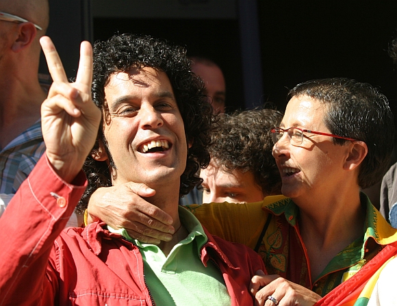 Gay rights activist and member of the Spanish Socialist Workers' Party executive board Pedro Zerolo (left) flashes a victory sign outside Madrid's parliament