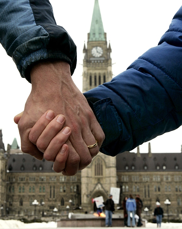 A married couple hold hands in front of the Canadian Parliamentary building in Ottawa