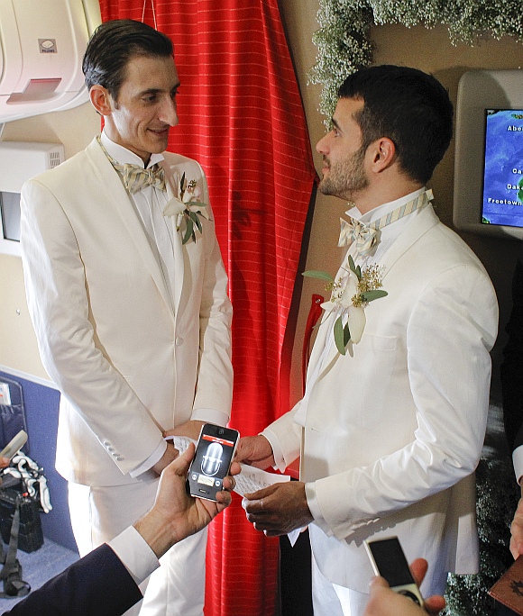 Aleksander Mijatovic (left) and his partner Shantu Bhattacharjee exchange personal vows after they were married at a civil wedding ceremony onboard a Scandinavian Airlines flight from Stockholm to Newark