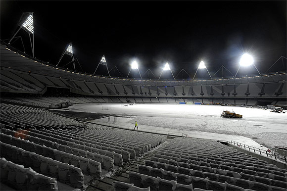 Floodlights illuminate a worker after Britain's Prime Minister David Cameron switched on the floodlights of the Olympic stadium at the Olympic park in Stratford, east London