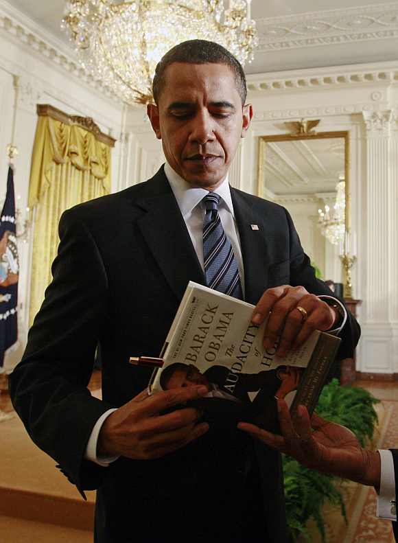 Obama prepares to sign his book for a participant at a small business event in Washington