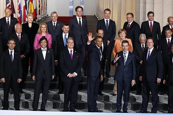 US President Barack Obama waves alongside Secretary General of NATO Anders Fogh Rasmussen as NATO heads of state gather for a family photo at Soldier Field in Chicago