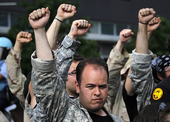 US war veterans raise their hands in solidarity after throwing their medals towards the site of the NATO Summit in Chicago. Nearly 50 veterans threw service medals into the street near the summit site in protest. Baton-swinging police clashed with anti-war protesters marching on the NATO summit in Chicago on Sunday and a lawyers' group representing the demonstrators said at least 12 people were injured, some with head wounds from police batons