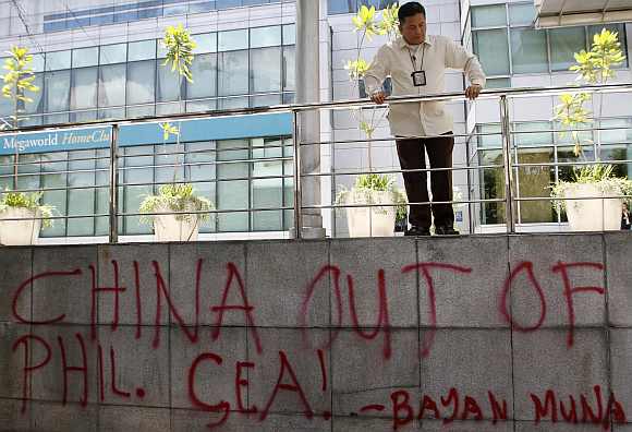 A security guard looks at graffiti done by activists in front of the Chinese consulate demanding the withdrawal of Chinese ships from the disputed Scarborough Shoal in the South China Sea during a protest in Manila's Makati financial district