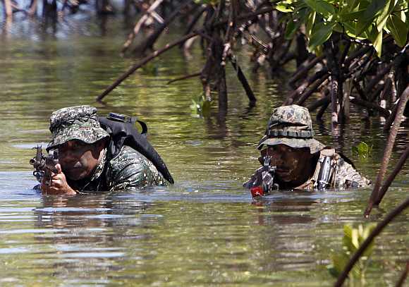 A Philippine and a US marine soldier wade in shallow water in a bay during a amphibious raid as part of a Philippine-US joint military exercise in Ulugan bay, western coast of Philippines