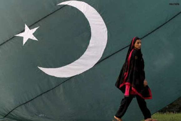 A Pakistani Hindu walks by a giant flag of Pakistan