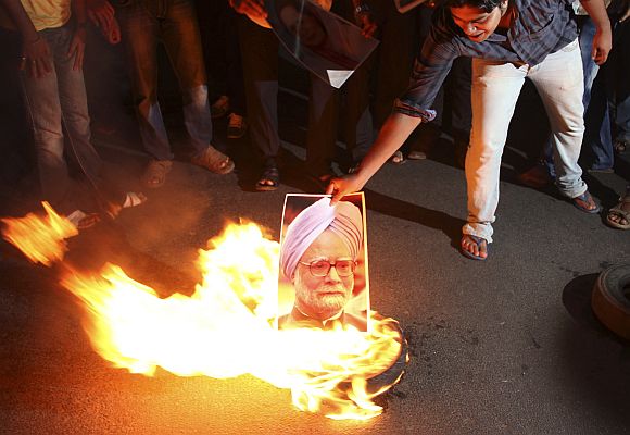 A protester burns a portrait of India's Prime Minister Manmohan Singh during a protest against the proposed rise in petrol prices in Orissa