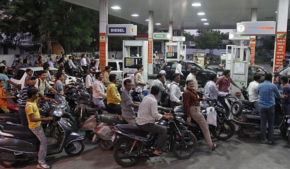 Motorcyclists crowd a fuel station to fill up on petrol in Ahmedabad