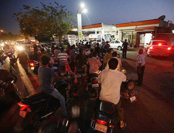 Motorcyclists form a line outside of a fuel station as they queue to fill up on petrol in Ahmedabad