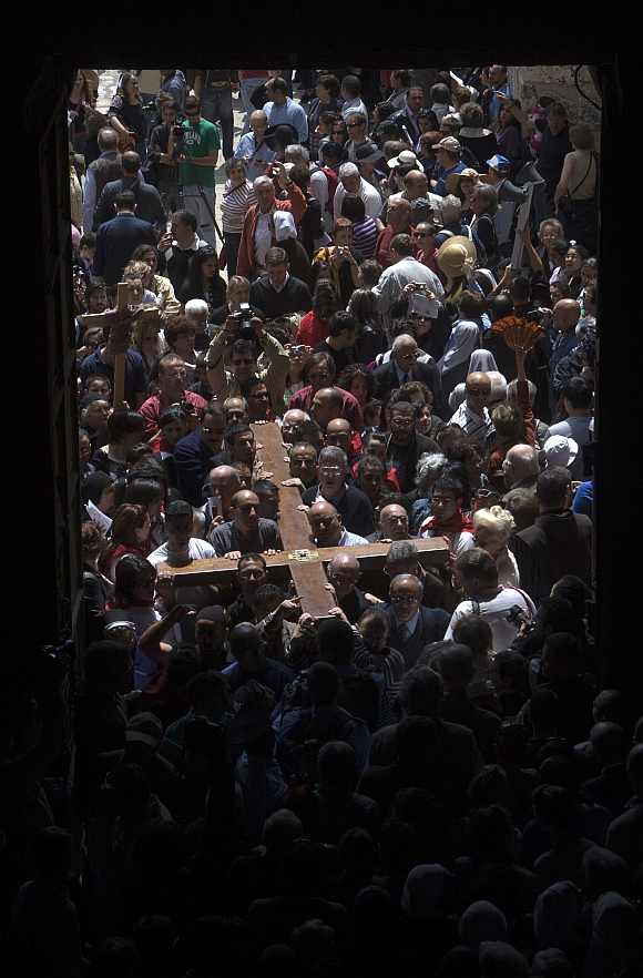 Worshippers carry a cross into the Church of the Holy Sepulcher, also known as the Church of the Resurrection, during the Good Friday procession in Jerusalem's Old City