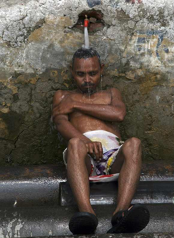 A man cools himself under a tap to beat the heat in Allahabad