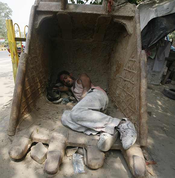 A labourer sleeps inside an excavator bucket on a hot day in Noida, Uttar Pradesh
