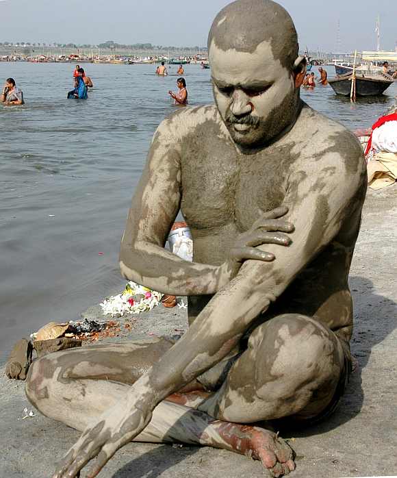 A man cools himself with mud on his body at the Ganges river in Allahabad