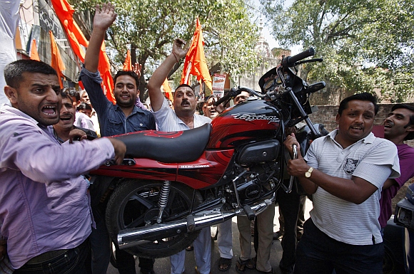 Activists from Shiv Sena carry a motorcycle as they shout slogans during a protest against the price hike in petrol, in Jammu