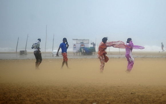 Women shield their faces during strong winds at Marina beach in Chennai
