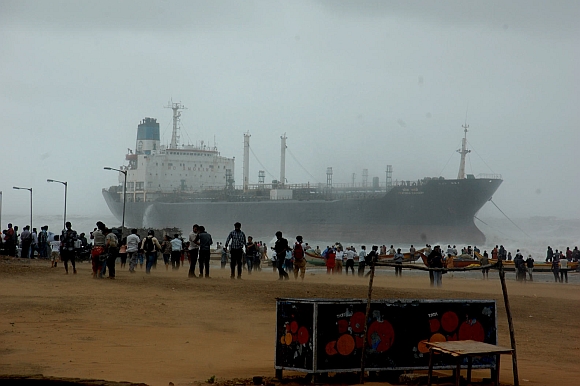 Onlookers watch ship Pratibha Cauvery, which ran aground allegedly due to strong winds, on the bay of Bengal coast, in Chennai