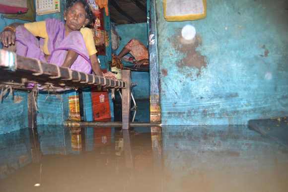 A old woman sits in her flooded house in an Andhra village