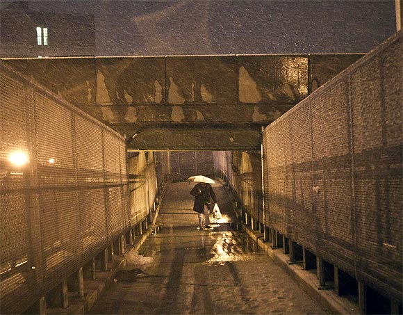 A man walks across an overpass during a nor'easter, also known as a northeaster storm, in the Red Hook Neighborhood of New York