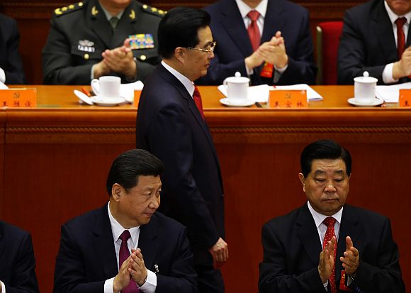 China's Vice President Xi (seating, left) applauds as President Hu walks past at the Great Hall of the People in Beijing