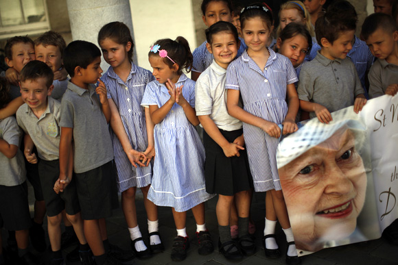 School children hold a banner with a picture of Queen Elizabeth II during her Diamond Jubilee celebrations