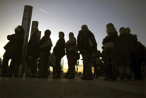 Commuters wait for buses at Atocha rail station during a 24-hour nationwide general strike in Madrid