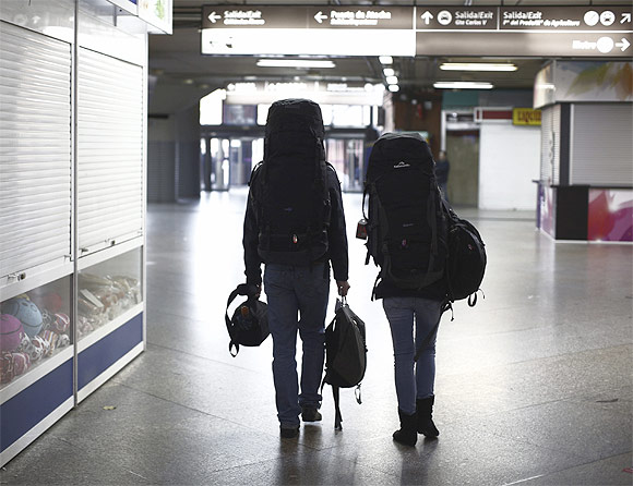 Backpackers walk through a nearly empty terminal at Atocha rail station in Madrid