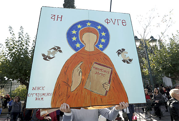 A protester holds a sign with a painting mocking an Orthodox icon during an anti-austerity rally by Greece's public servants unions in Athens