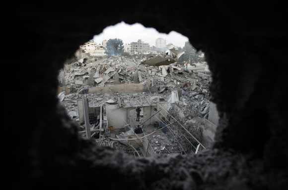 Palestinians are seen through a hole in the wreckage as they inspect the destroyed office building of Hamas Prime Minister Ismail Haniyeh in Gaza City