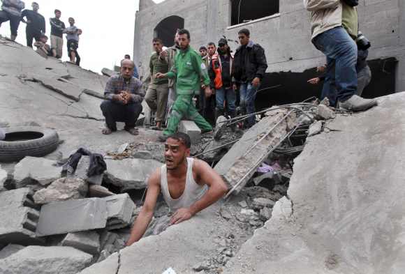 A Palestinian searches for victims under the rubble of the destroyed house of a Hamas official after an Israeli air strike in Jabalya in the northern Gaza Strip
