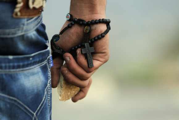 A Palestinian demonstrator wearing a rosary holds a stone during minor clashes with Israeli troops in protest against Israel's military operation in the Gaza Strip, in the West Bank village of Bir Zeit, near Ramallah