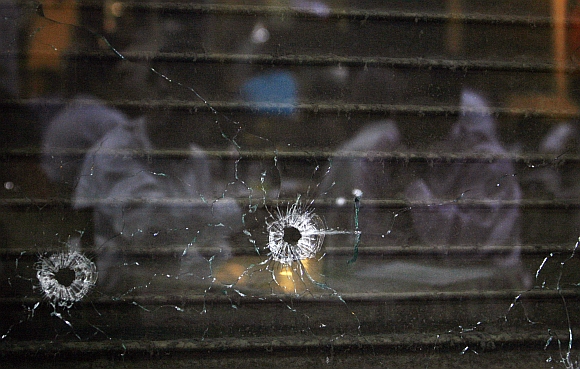 Customers are reflected in a glass pane with bullet holes in Cafe Leopold