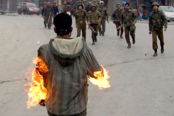 Security personnel rush towards a man who set himself on fire in Srinagar on Friday