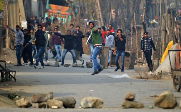 A protestor pelts stones towards security personnel during a clash in Srinagar on Friday