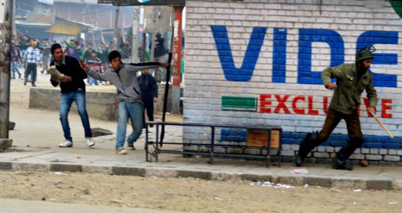 Protestors pelt a stone towards a police personnel in Srinagar on Friday