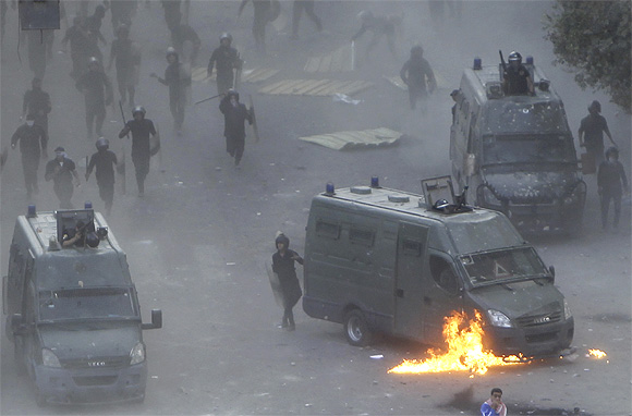 Flames burn around a police vehicle after protesters threw a molotov cocktail at it during clashes at Tahrir square