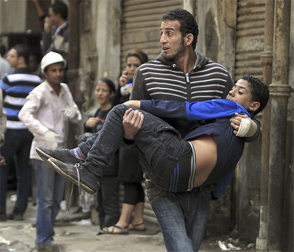 A protester carries an injured fellow protester during clashes with the police at Tahrir square