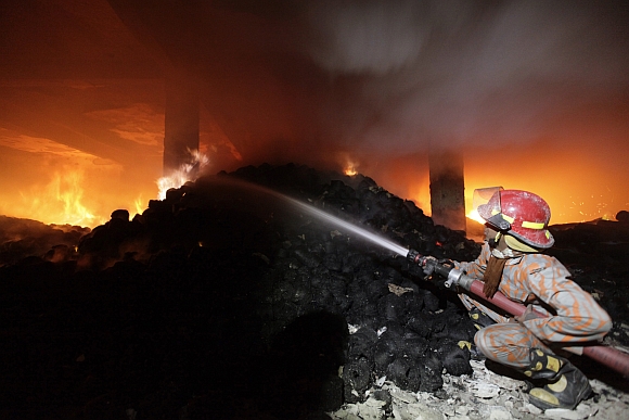 A firefighter tries to control a fire at a garment factory in Savar, outskirts of Dhaka