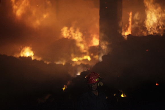 A firefighter tries to control a fire at a garment factory in Savar, outskirts of Dhaka