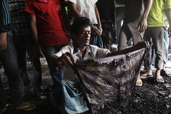 A man shows a piece of cloth which he says belong to his sister-in-law, a missing worker after a devastating fire in a garment factory which killed more than 100 people
