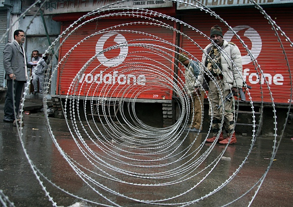 CRPF personnel lay out razor wire to block a road