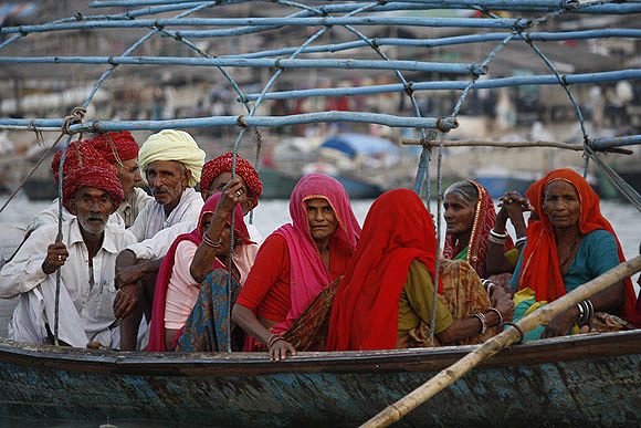 Pilgrims get onto a boat to take a dip in the Sangam