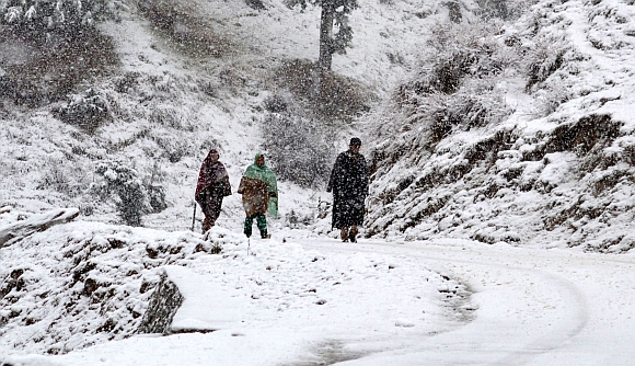 Locals take a walk in heavy snowfall on the Gulmarg-Tangmarg road