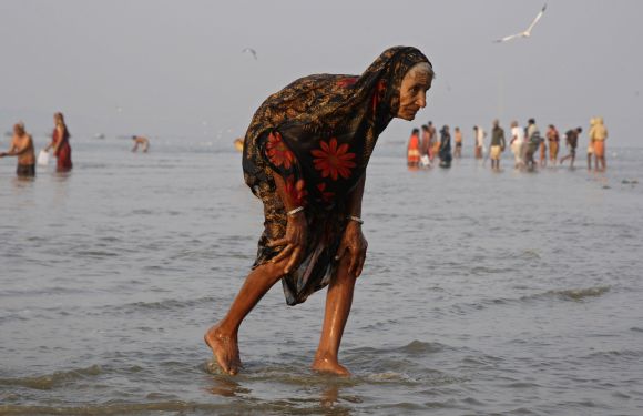 A devotee walks after taking a holy dip in Sangam, the confluence of the three holy rivers Ganga, Yamuna and Saraswati.