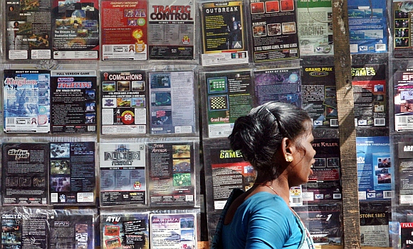 A woman walks past pirated DVDs and software on sale at a street side hawker shop in Mumbai