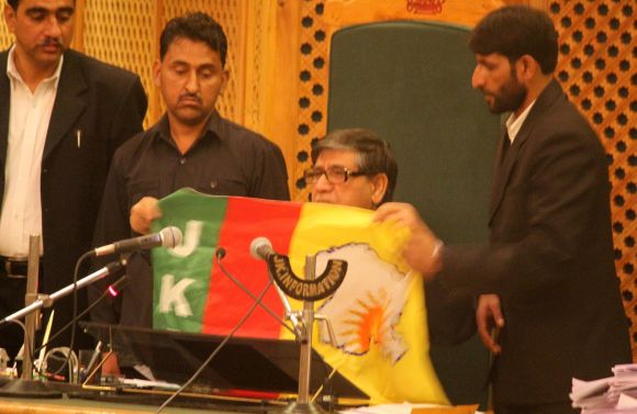J&K assembly speaker Lone inspects the flag recovered from the youth