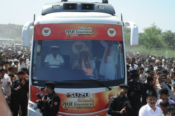Modi waves to his supporters from his campaign bus during his ongoing yatra