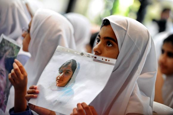 Students hold pictures of schoolgirl Malala Yousufzai, who was shot by the Taliban, during a tribute at the Pakistani Embassy in Abu Dhabi
