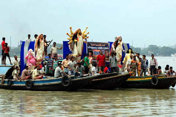 A Durga idol is ferried across the Ganga by members of Bali Sarbojonin Durgotsav Committee